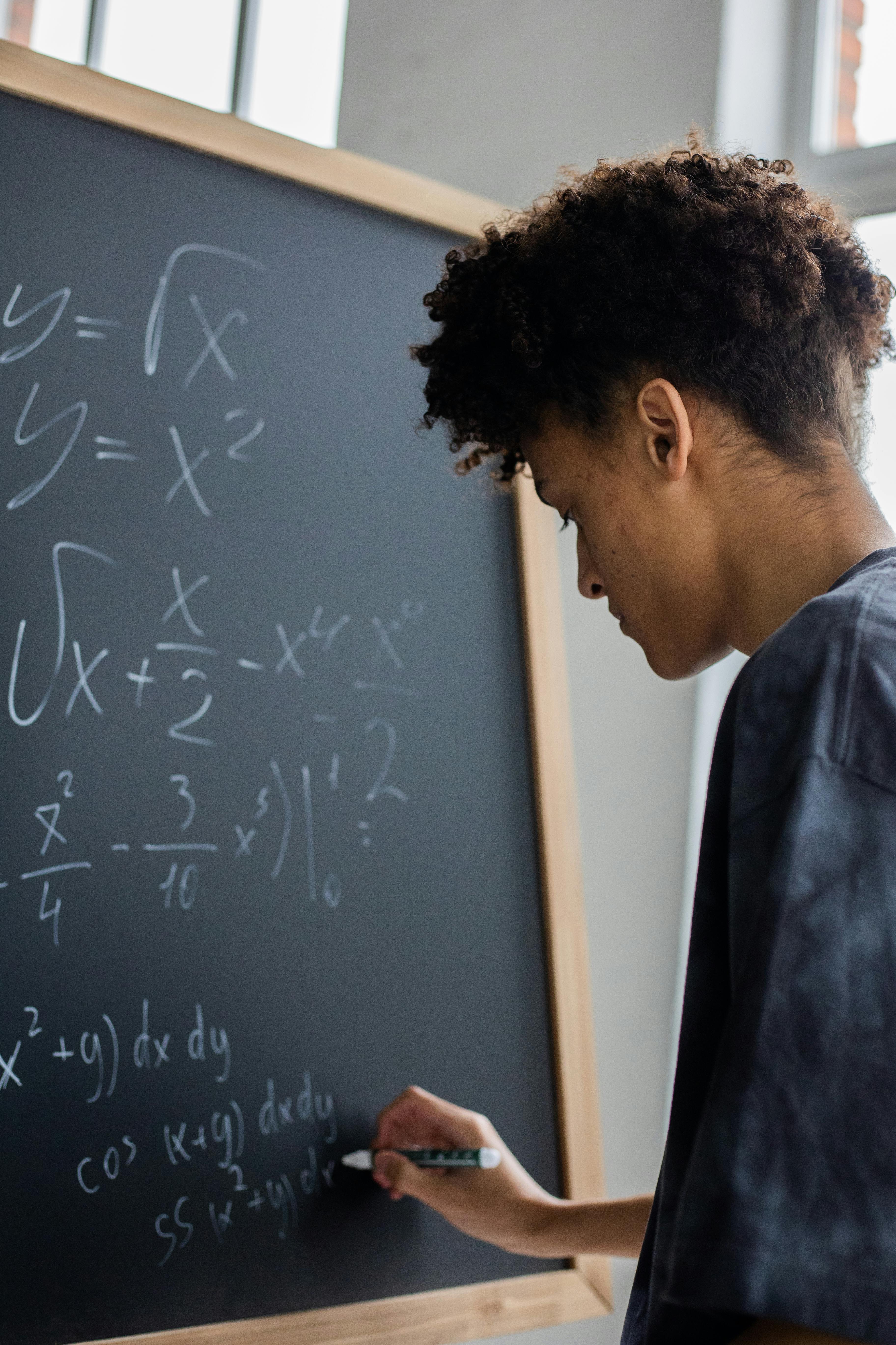 Expert online GCSE Maths tutor helping student solve complex equations on a blackboard