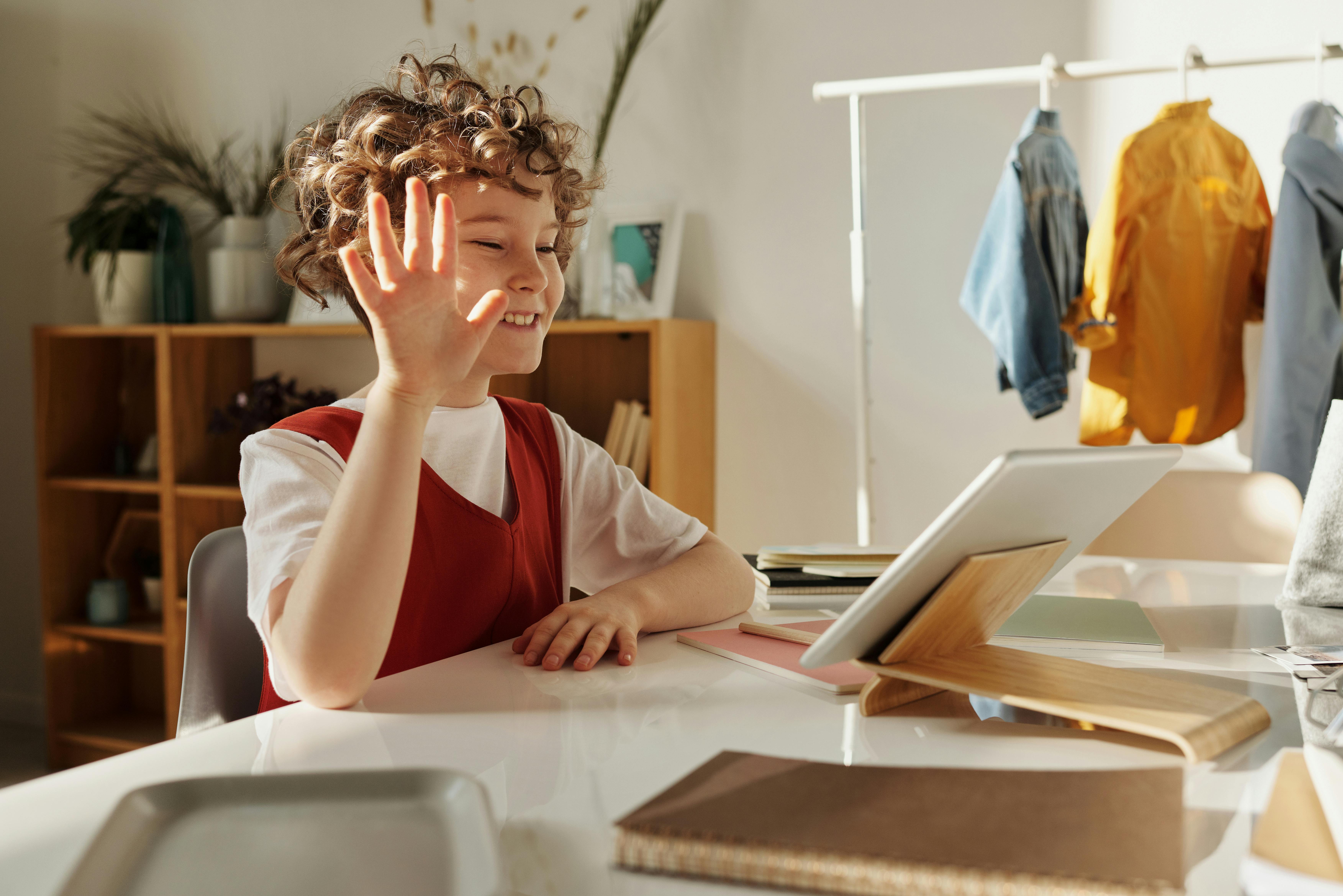 Young student waving at their expert online GCSE Maths tutor during an engaging virtual lesson