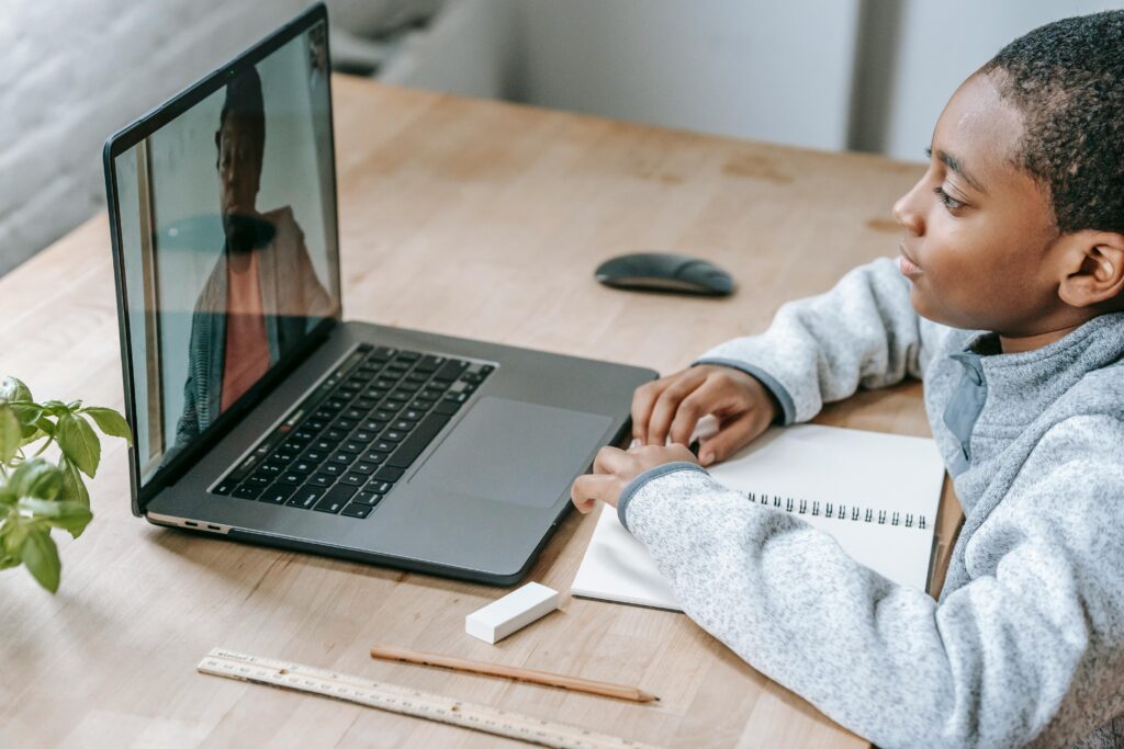 Young student attentively participating in an online tutoring session via laptop for GCSE exam preparation.